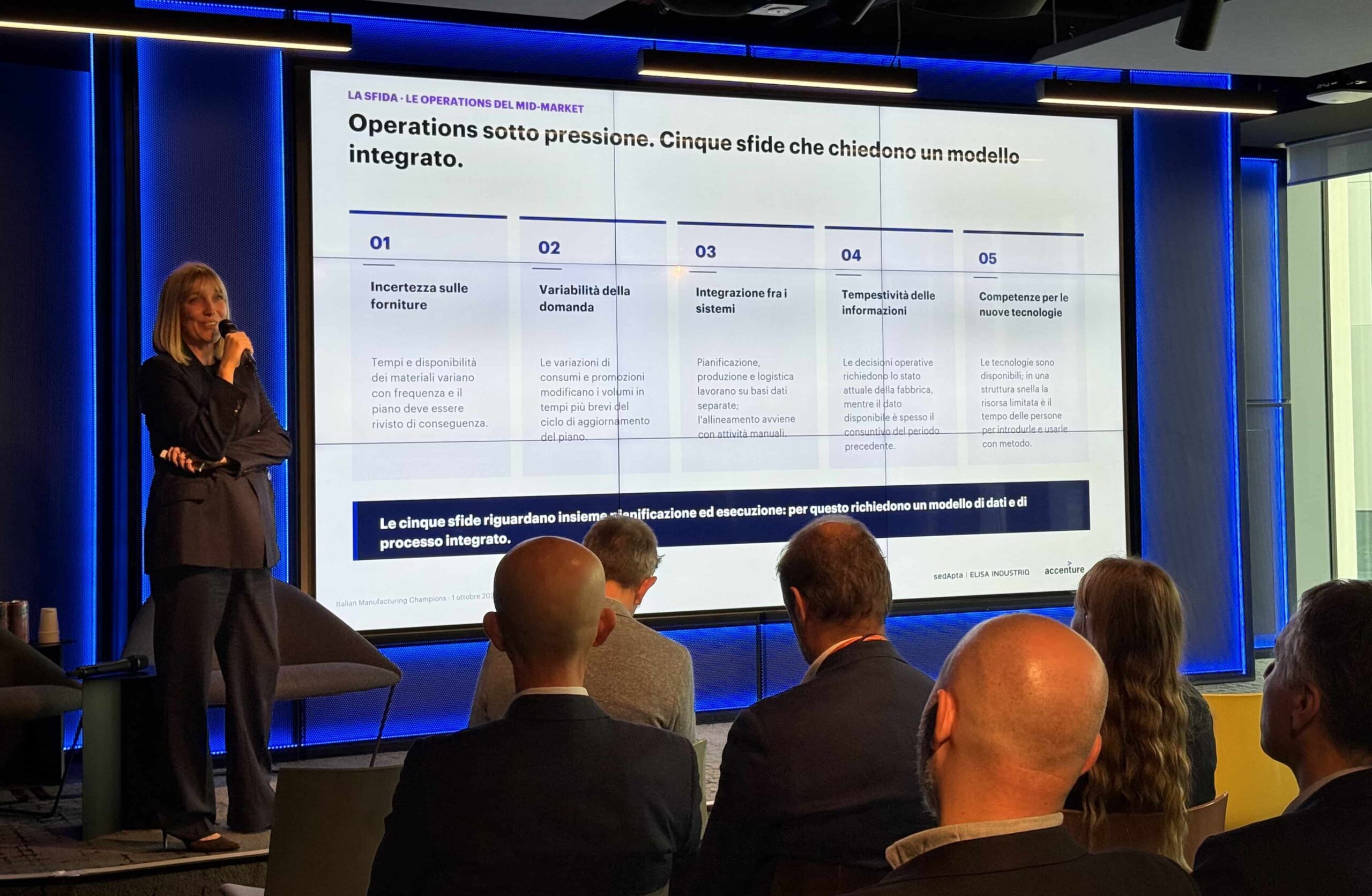 Benedetta Cuttica, CEO di sedApta, parla con il microfono in mano davanti allo schermo con la slide sulle cinque sfide delle operations del mid-market, all’evento Italian Manufacturing Champions al Mixic di Assago